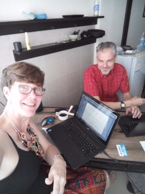 P.J. & Doug working in Thailand, small desk, laptops & coffee ...